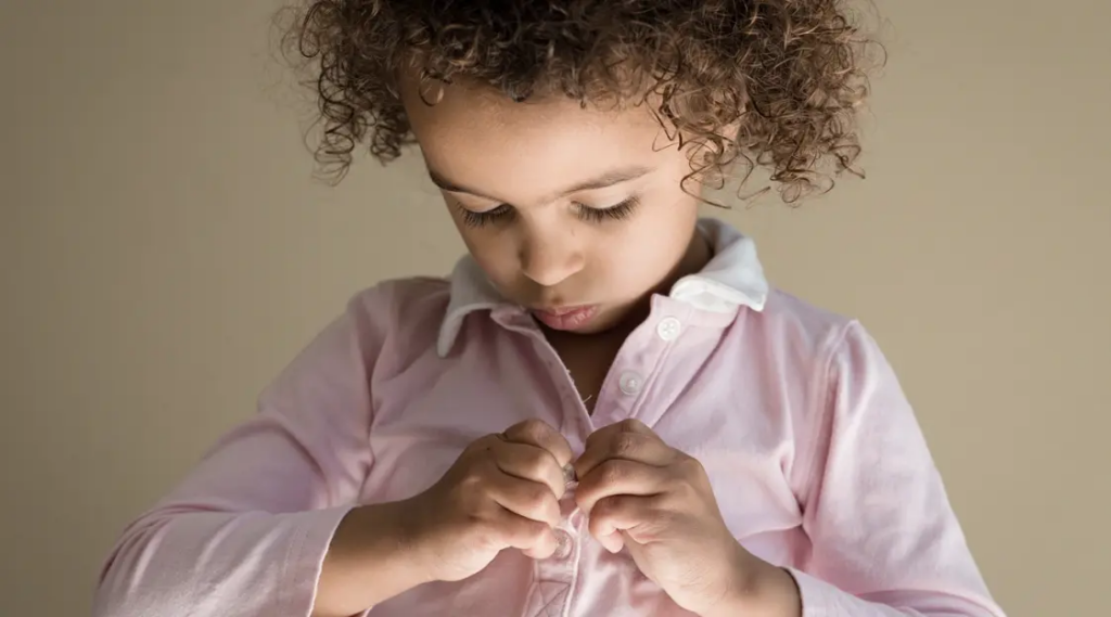 autonomia del bambino nel vestirsi - bambina si allaccia i bottoni da sola